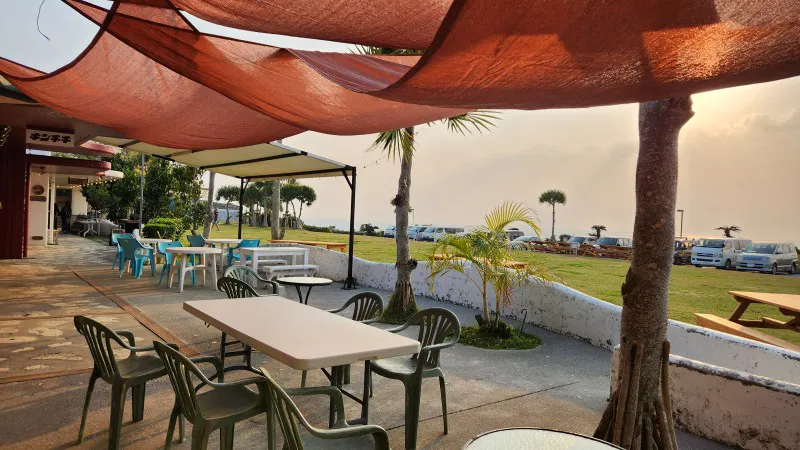 Outdoor terrace with tables and sea view near Yomitan Coral Farm