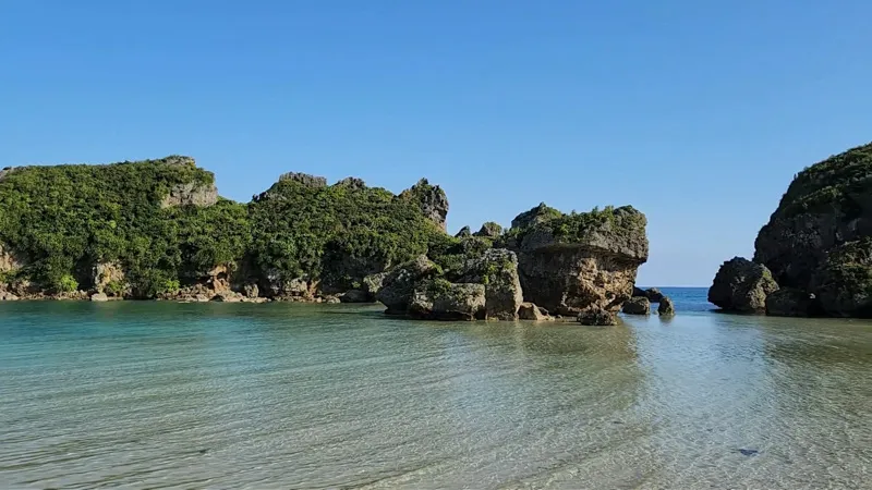 Formations rocheuses recouvertes de verdure dans des eaux turquoise limpides à Hamahigajima
