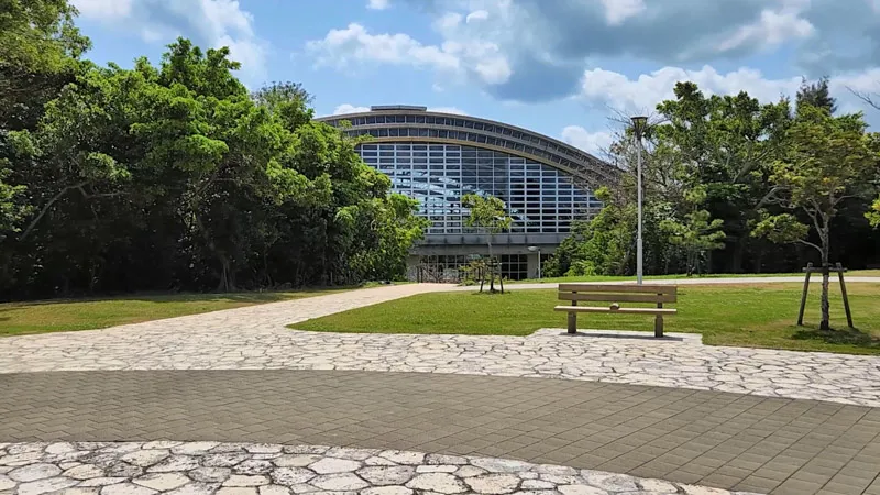 Large glass hall surrounded by greenery at Kitanakagusuku Sports Park Okinawa