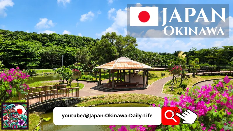 Wooden gazebo surrounded by lush greenery, bridges, and flowered ponds under a bright blue sky at the Okinawa Family Sports Park in Japan.