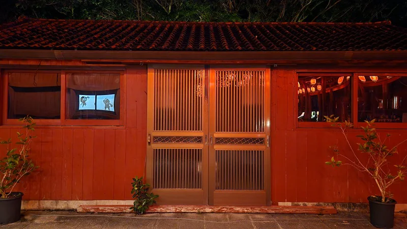Traditional wooden building with sliding doors and shadow projections at Murasaki Mura