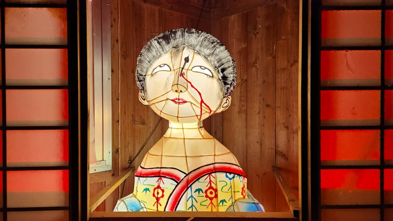 Illuminated Jurimajimum yokai doll lantern with cracked face and kimono at the Ryukyu Yokai Festival