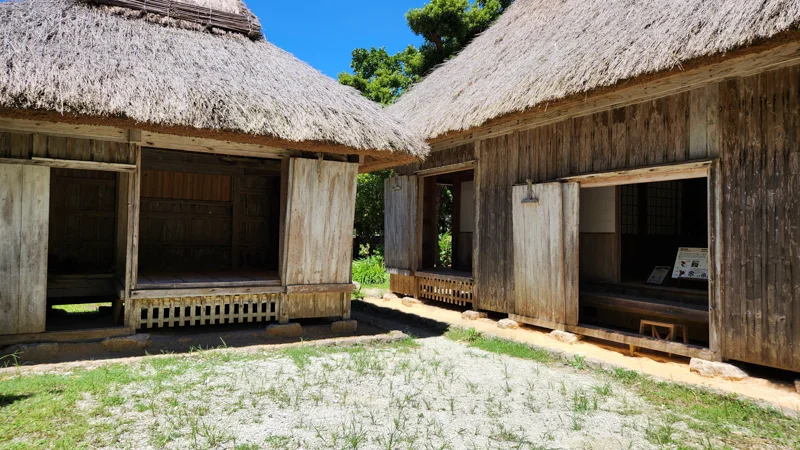 Two traditional wooden houses with thatched roofs in Okinawa