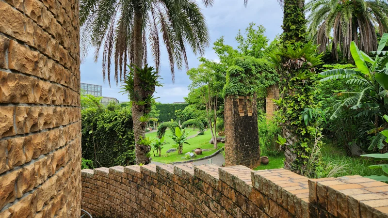 Stone walkway with palm trees and lush greenery at the Tropical Dream Center in Okinawa