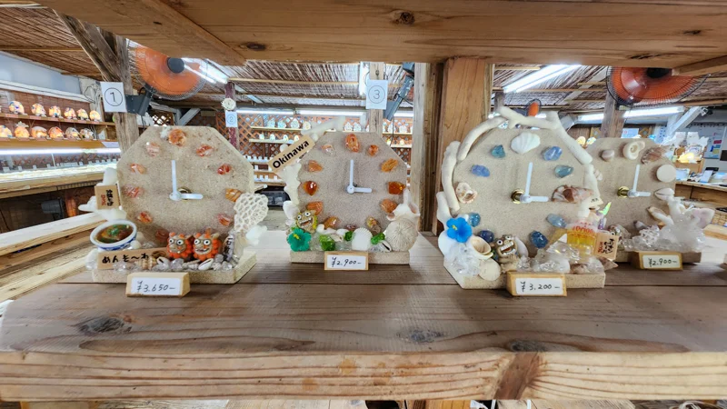 Handmade Okinawan shell clocks with shisa and coral decorations at Murasaki Mura