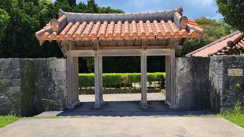 Traditional Okinawan wooden gate with red tiles at the entrance of a historic residence.