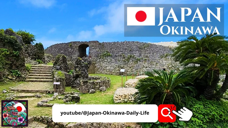 View of the Nakagusuku Castle ruins in Okinawa with stone walls, palm trees and a Japan Okinawa promotional banner.