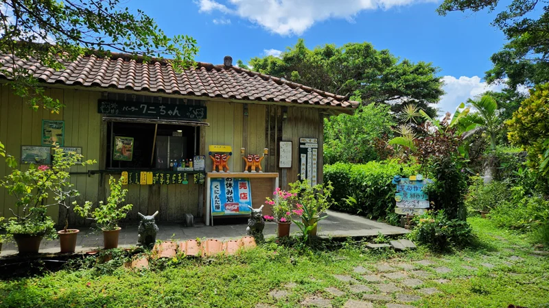 Traditional Okinawan shop with tiled roof surrounded by greenery