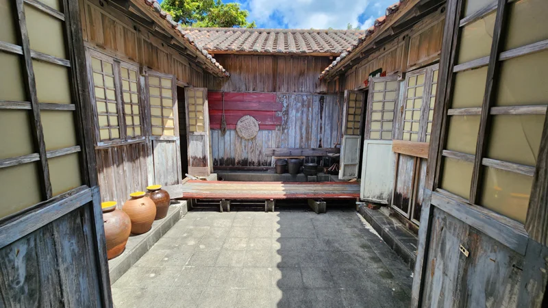 Old Okinawan wooden house with tiled roof and clay jars