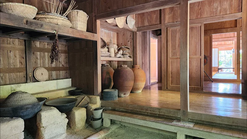 Clay jars, baskets, and kitchen tools displayed inside the Jitūdē’s traditional Okinawan house.