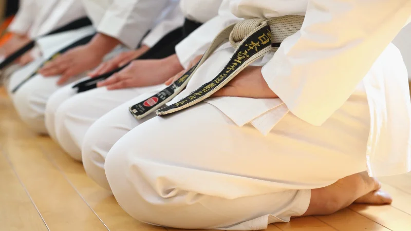 Karate students kneeling in traditional dojo training.