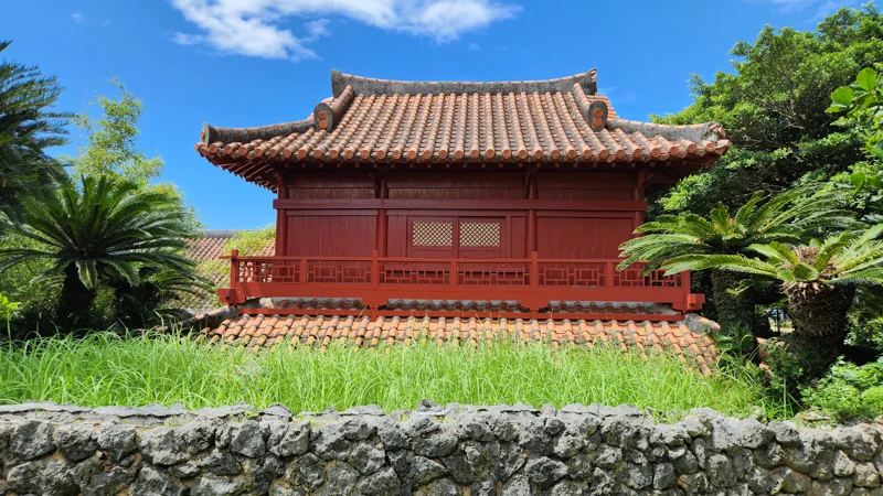 Traditional red wooden Okinawan house with tiled roof and stone wall