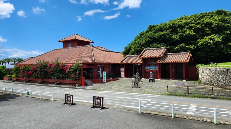 Main entrance of Murasaki Mura cultural park in Yomitan with red tiled roof buildings and shisa statues