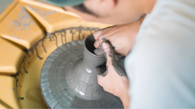 Hands shaping clay on a potter’s wheel
