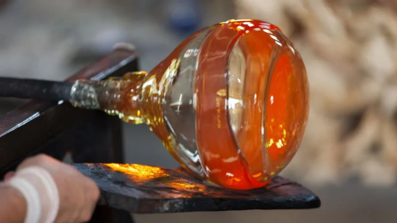 Glowing glass being shaped on a support