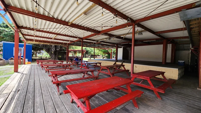 Red wooden picnic tables under a covered terrace at Murasaki Mura