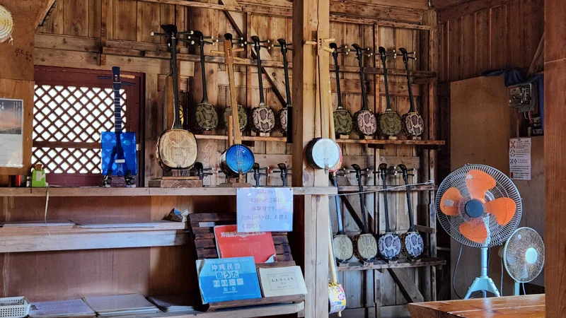 Traditional Okinawan sanshin instruments displayed on wooden wall racks