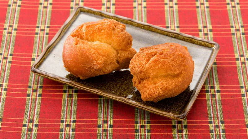 Two Okinawan sata andagi donuts on a plate.