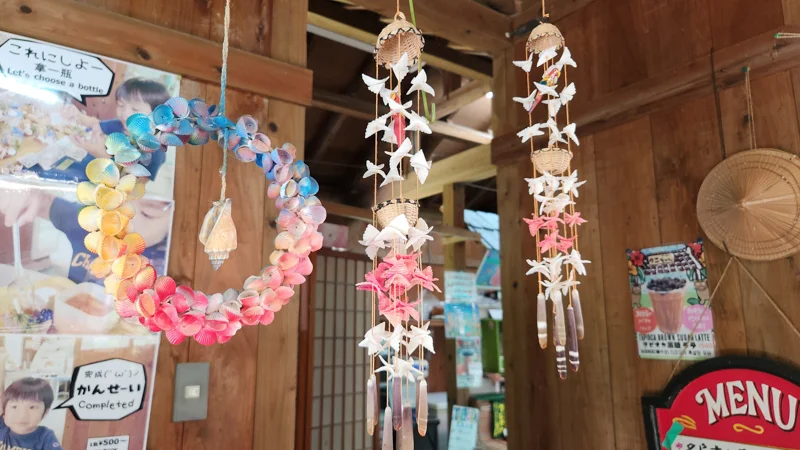 Colorful shell crafts and wind chimes hanging in Murasaki Mura workshop