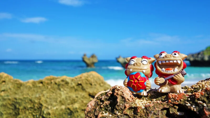 Colorful Shisa statues on rock by Okinawan beach.