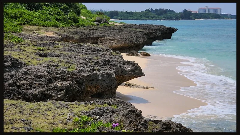 Sandy beach bordered by coral rocks at Cape Zanpa