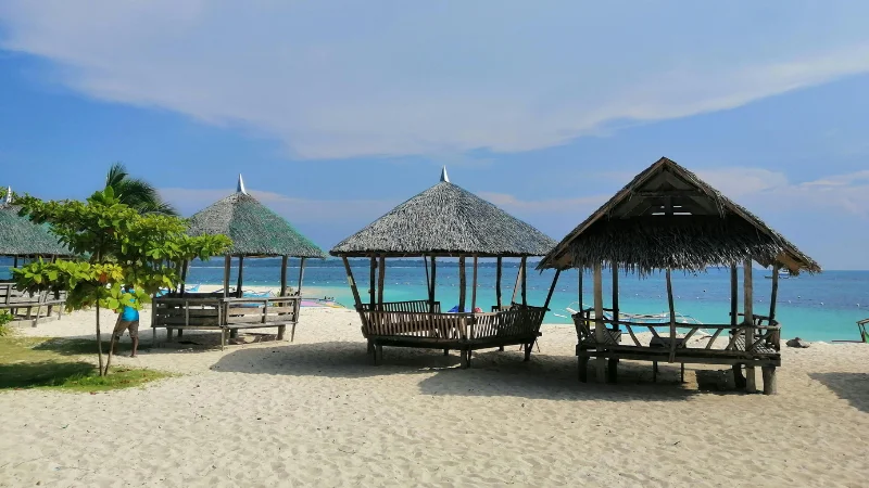 Wooden huts on Zanpa Beach with white sand and turquoise sea