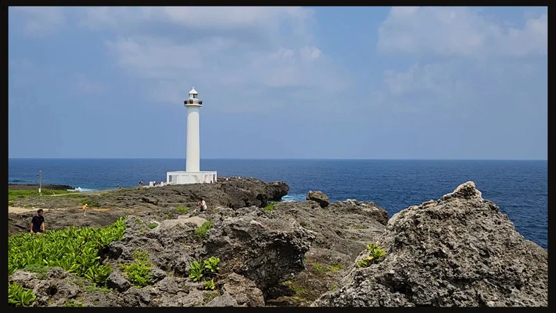 White lighthouse at Cape Zanpa surrounded by greenery and rocks