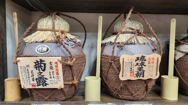Large traditional clay jars wrapped in rope and straw, used for aging Awamori in Okinawa.