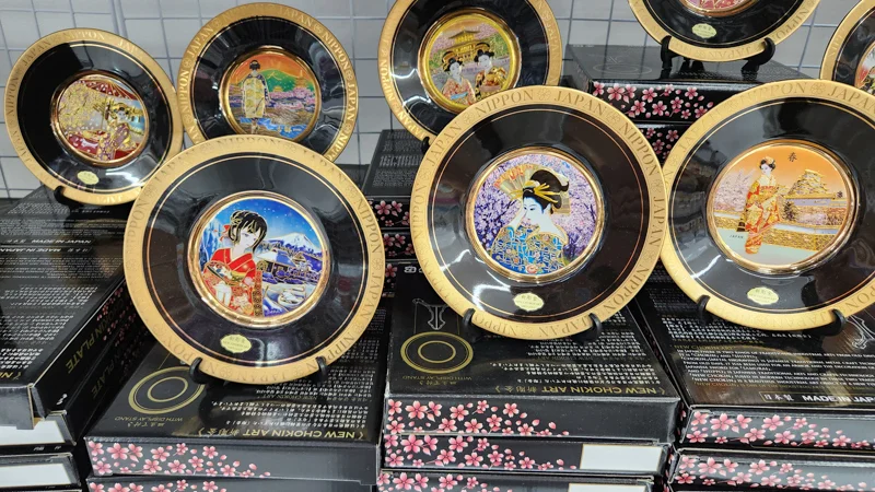Decorative plates featuring geisha and Japanese landscape illustrations displayed in a store.