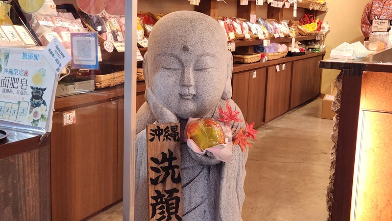 Stone Jizo statue holding a decorative item inside a traditional Okinawan shop.