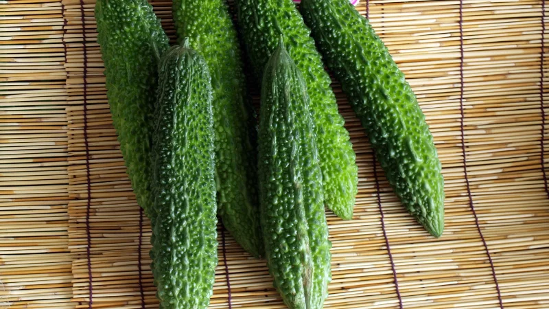 Fresh green goya bitter melons on a bamboo mat