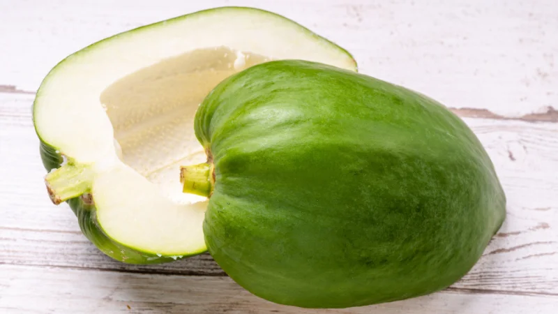 Fresh green papaya cut open on a wooden surface