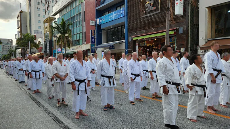 Large group of karate practitioners in white uniforms lined up on Kokusai Dori during a martial arts event in Naha, Okinawa.