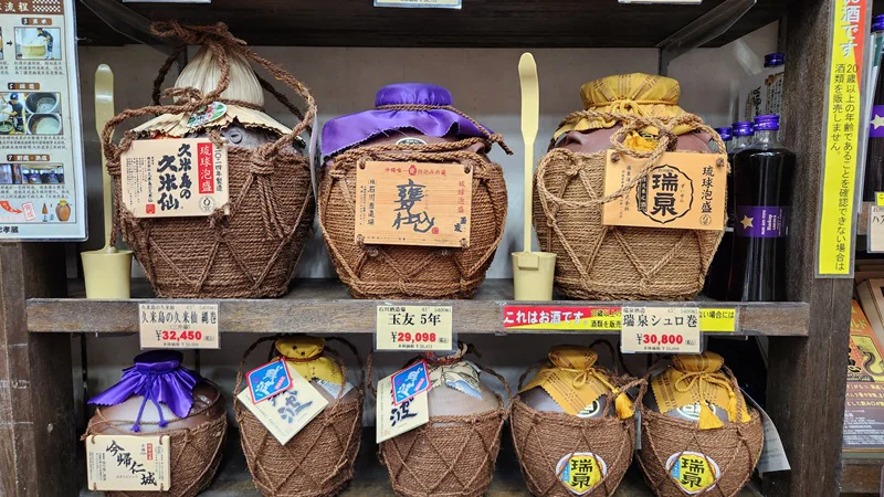 Display of traditional awamori jars wrapped in straw on store shelves