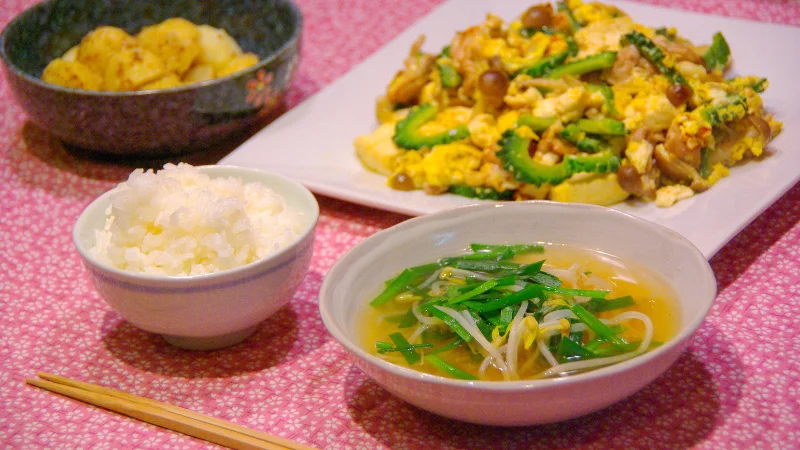 Table set with goya champuru, rice, miso soup, and potatoes