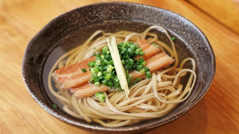 Bowl of Okinawa soba with pork belly and green onions