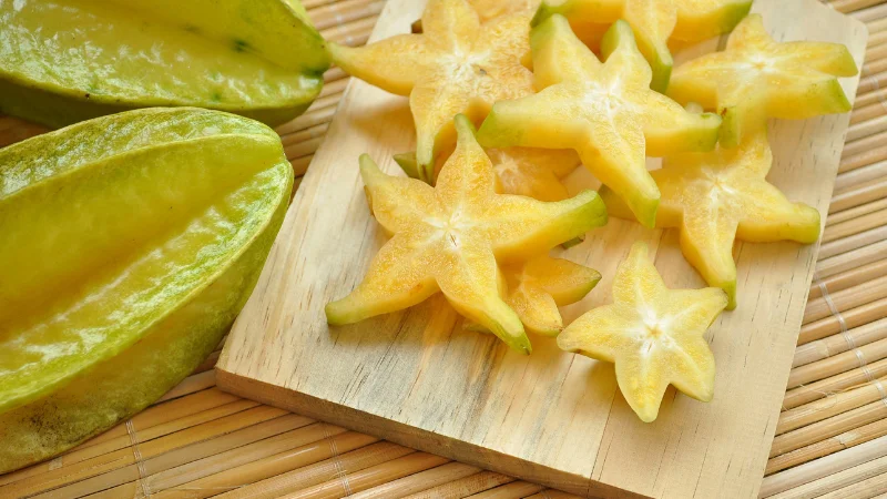 Sliced starfruit pieces arranged on a wooden board