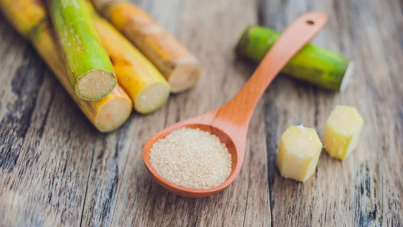 Fresh sugarcane pieces with a spoonful of raw sugar