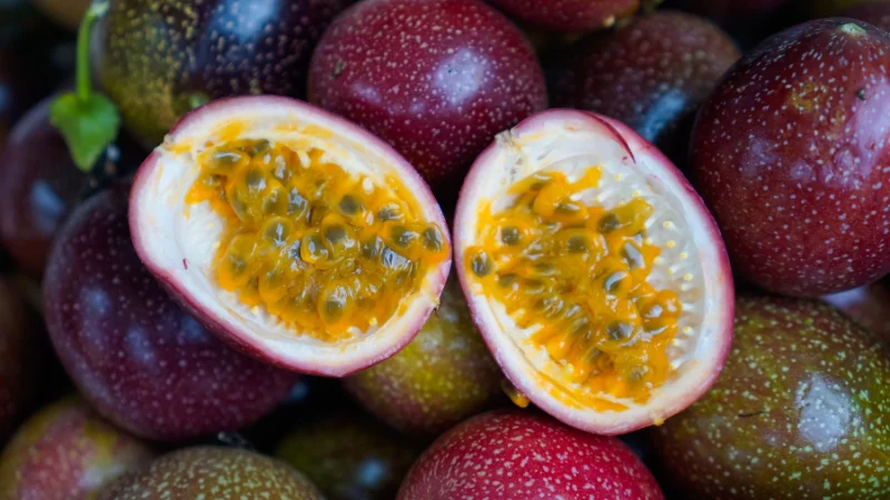 Fresh purple passion fruits with one cut open showing seeds