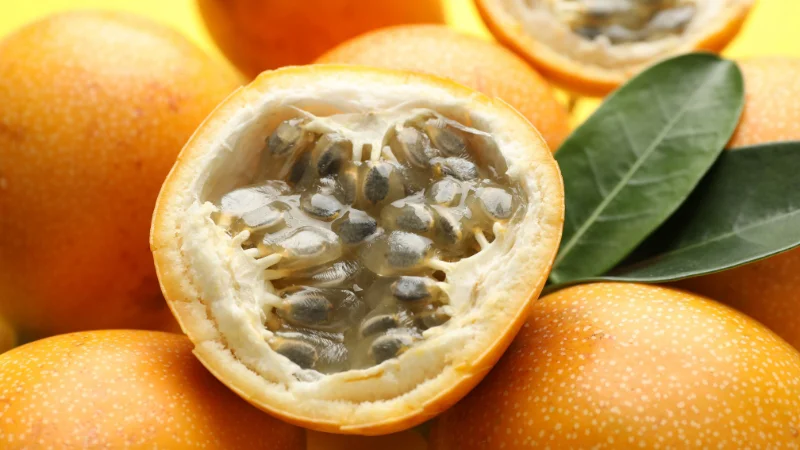 Fresh yellow passion fruit with one cut open to reveal juicy seeds