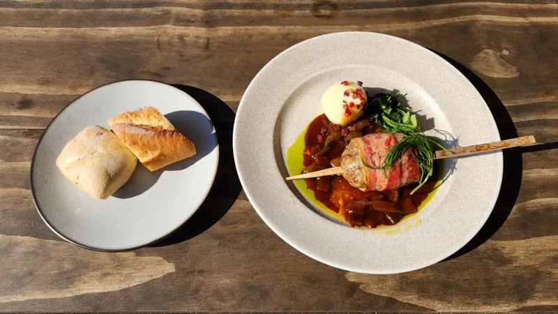 Gourmet dish with vegetables, wrapped skewer, mashed potato, and bread at Junglia Okinawa