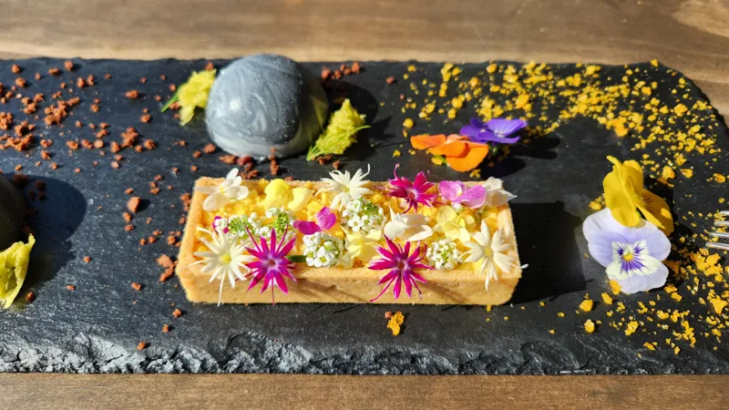 Floral tart decorated with colorful edible flowers served on a stone plate