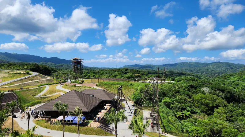 View over Junglia Okinawa with attractions, observation tower, and tropical mountains