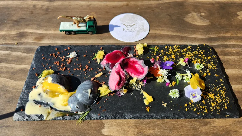 Destroyed dessert with colorful filling and edible flowers on a stone plate