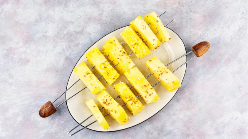 Pieces of Okinawa pineapple arranged on metal skewers