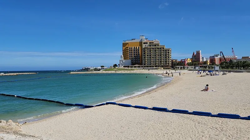 Wide sandy beach with turquoise water and resort buildings at Sunset Beach Chatan Okinawa