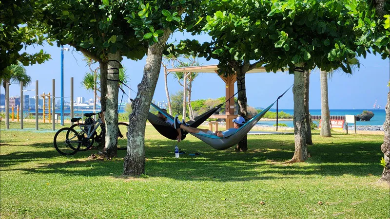 People resting in hammocks under trees near Sunset Beach Chatan Okinawa
