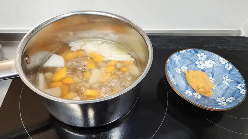 Beef soup simmering with daikon radish, carrot, and onion in a pot