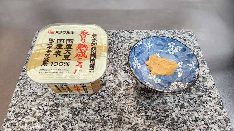 Natural Japanese miso paste served on a small plate next to miso container