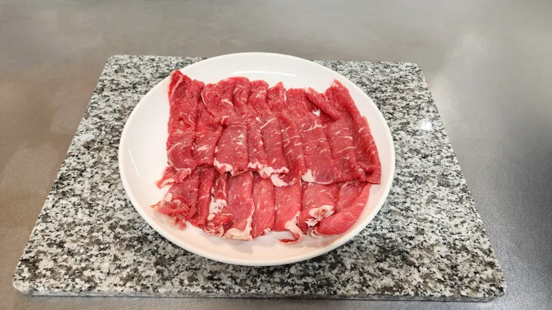 Plate of thinly sliced raw beef prepared for Japanese home cooking